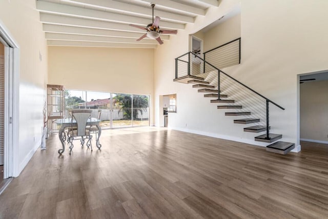 unfurnished living room with hardwood / wood-style flooring, ceiling fan, beamed ceiling, and high vaulted ceiling