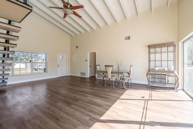 unfurnished living room with beamed ceiling, plenty of natural light, wood-type flooring, and high vaulted ceiling