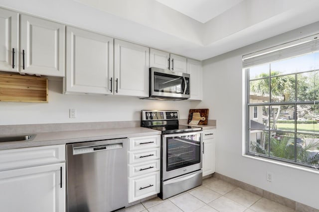 kitchen featuring white cabinetry, sink, light tile patterned floors, and stainless steel appliances