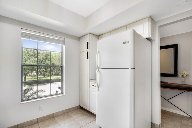 kitchen featuring white cabinets, light tile patterned floors, and white refrigerator