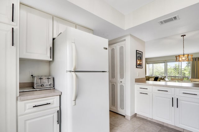 kitchen featuring pendant lighting, a notable chandelier, white cabinets, white fridge, and light tile patterned flooring