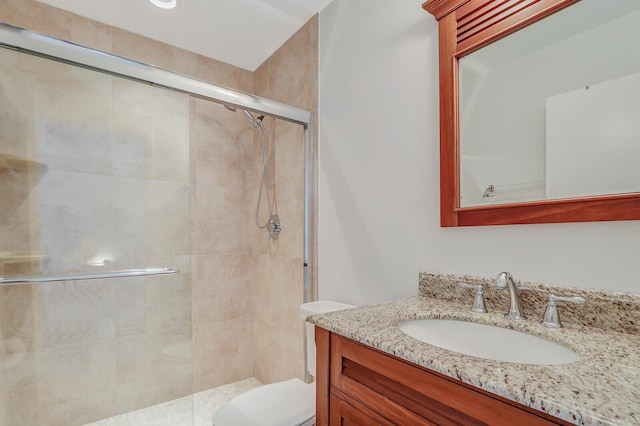 bathroom featuring vanity, toilet, and a shower with shower door