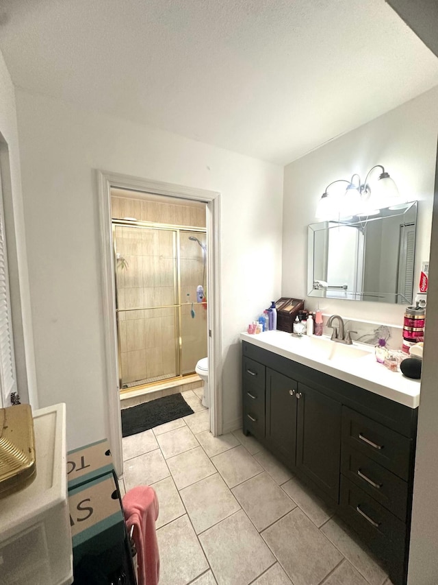 bathroom featuring vanity, tile patterned flooring, toilet, a textured ceiling, and an enclosed shower