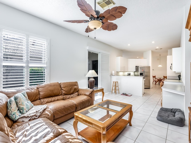 tiled living room featuring ceiling fan and a textured ceiling