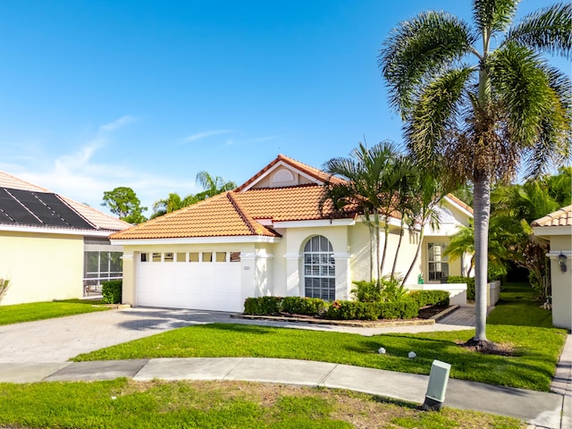 mediterranean / spanish house with a garage and a front lawn