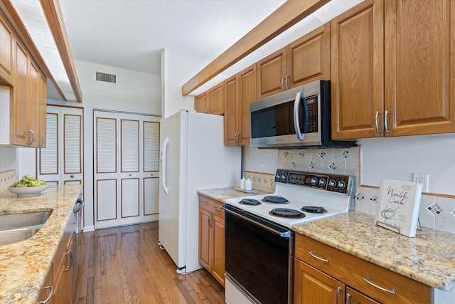 kitchen featuring tasteful backsplash, light stone counters, white appliances, and light wood-type flooring