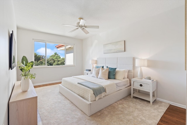 bedroom featuring ceiling fan, light hardwood / wood-style floors, and a textured ceiling