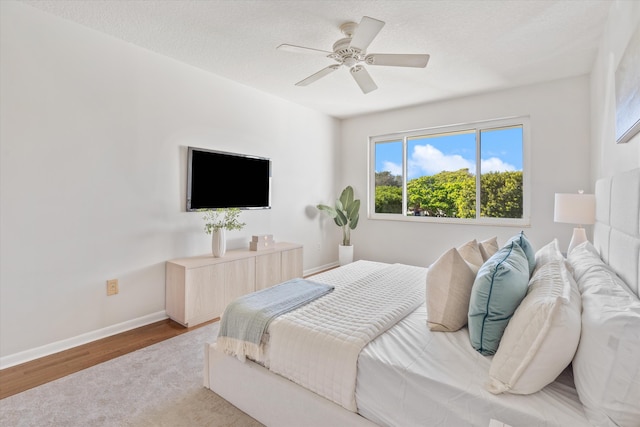 bedroom with wood-type flooring, a textured ceiling, and ceiling fan