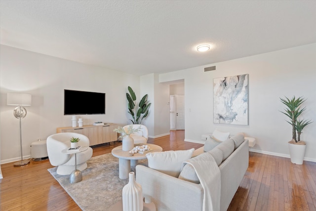 living room with light hardwood / wood-style floors and a textured ceiling