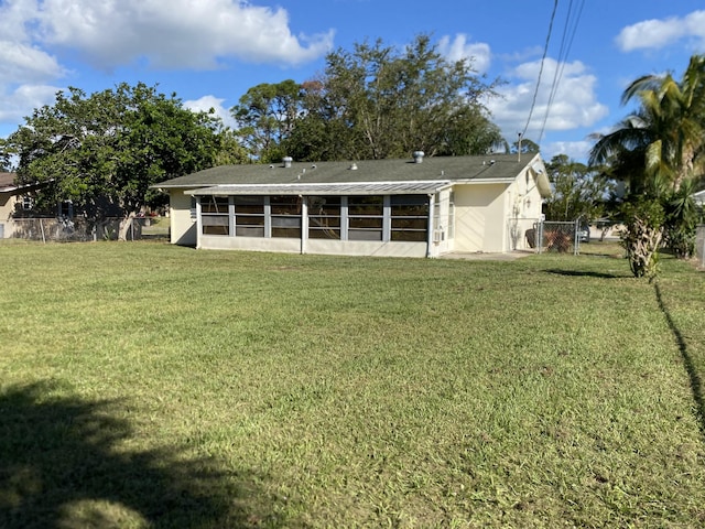 rear view of property featuring a sunroom and a lawn