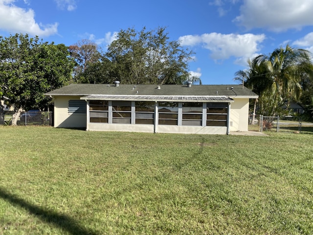 rear view of house with a sunroom and a lawn