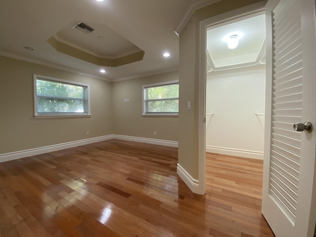 unfurnished room with hardwood / wood-style floors, a raised ceiling, and crown molding