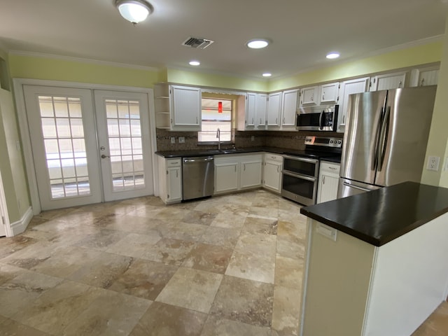 kitchen featuring white cabinetry, french doors, sink, tasteful backsplash, and appliances with stainless steel finishes