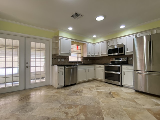 kitchen with white cabinetry, french doors, stainless steel appliances, tasteful backsplash, and ornamental molding