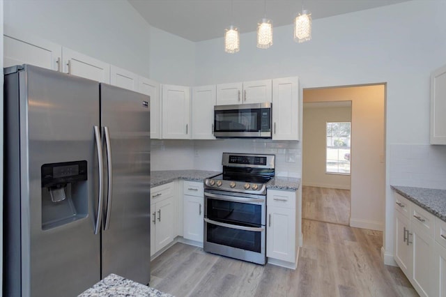 kitchen with white cabinets, backsplash, stainless steel appliances, and light hardwood / wood-style flooring