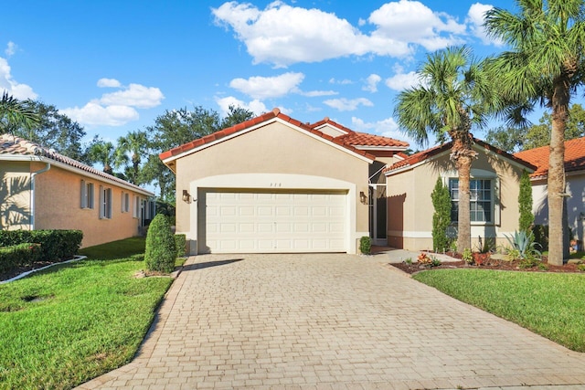 mediterranean / spanish house featuring a front lawn, a tile roof, stucco siding, decorative driveway, and an attached garage