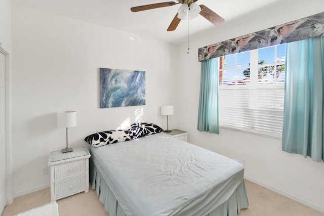 bedroom featuring light carpet, a ceiling fan, and baseboards