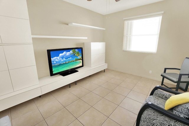 living area with light tile patterned floors, a ceiling fan, and baseboards