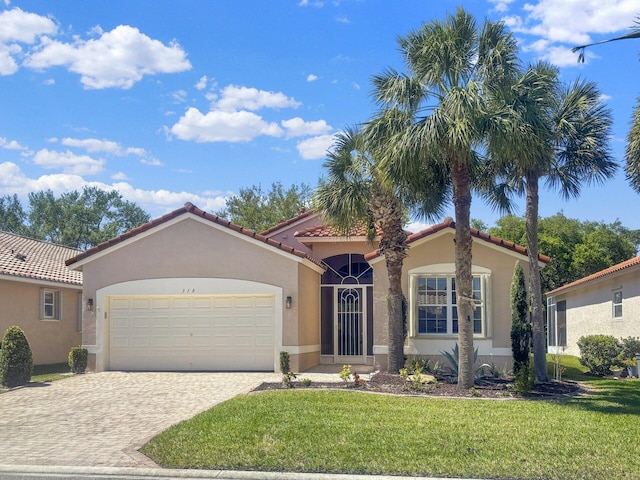 mediterranean / spanish house featuring a front yard, stucco siding, a garage, a tile roof, and decorative driveway