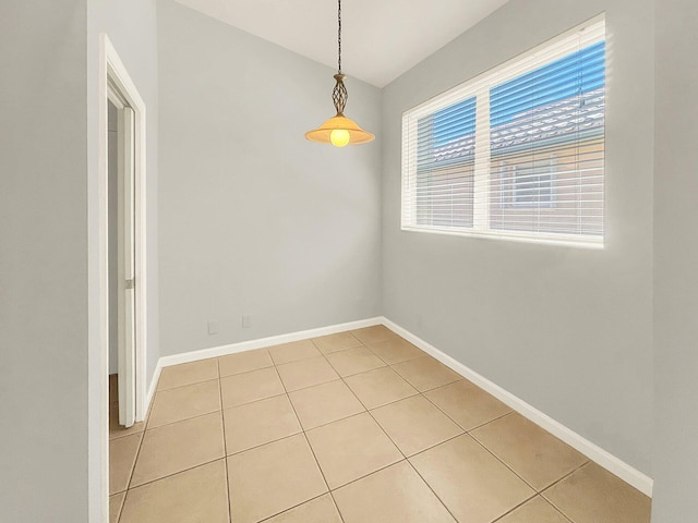 empty room with baseboards, lofted ceiling, and light tile patterned flooring