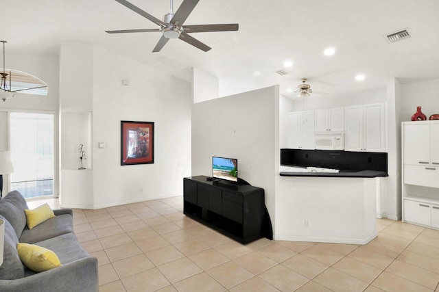 living room with light tile patterned floors, ceiling fan with notable chandelier, visible vents, and high vaulted ceiling