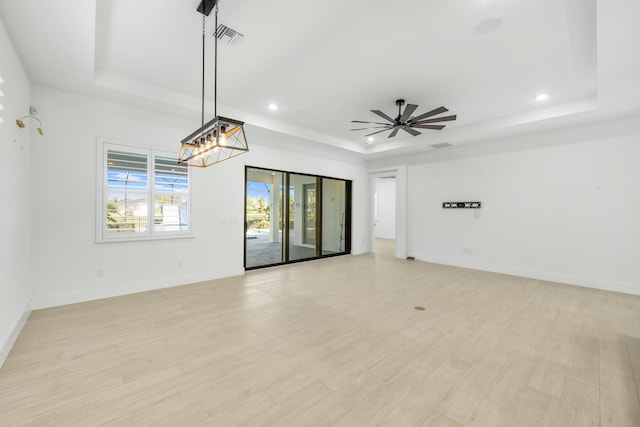 empty room featuring ceiling fan, light hardwood / wood-style floors, and a tray ceiling