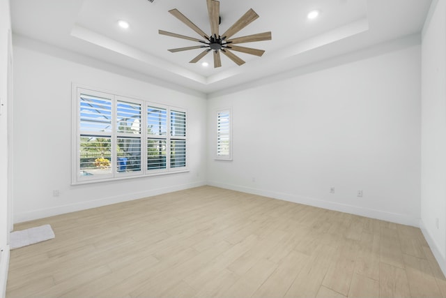 unfurnished room featuring light hardwood / wood-style flooring, a wealth of natural light, and a tray ceiling