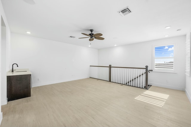 empty room with light hardwood / wood-style flooring, ceiling fan, and sink