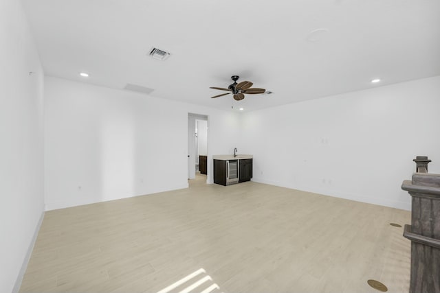 unfurnished living room featuring ceiling fan, sink, and light hardwood / wood-style floors