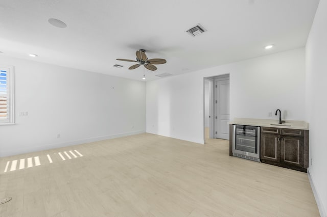 interior space featuring ceiling fan, light hardwood / wood-style floors, beverage cooler, and sink