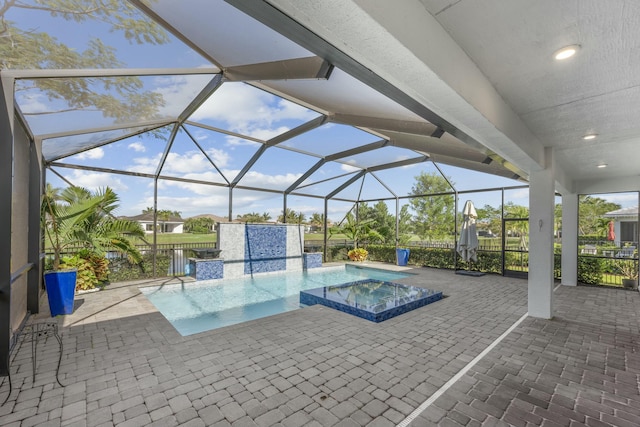 view of pool with an in ground hot tub, glass enclosure, and a patio area