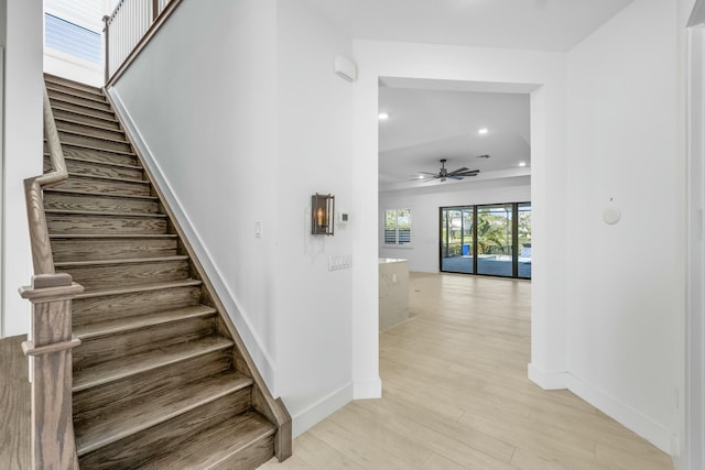 staircase with wood-type flooring and ceiling fan