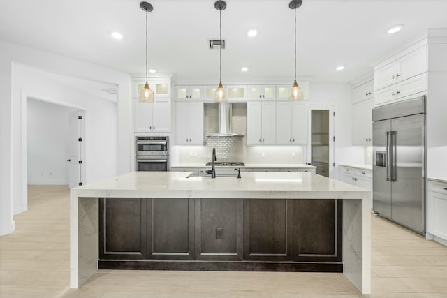 kitchen featuring stainless steel appliances, white cabinetry, a large island, and wall chimney range hood