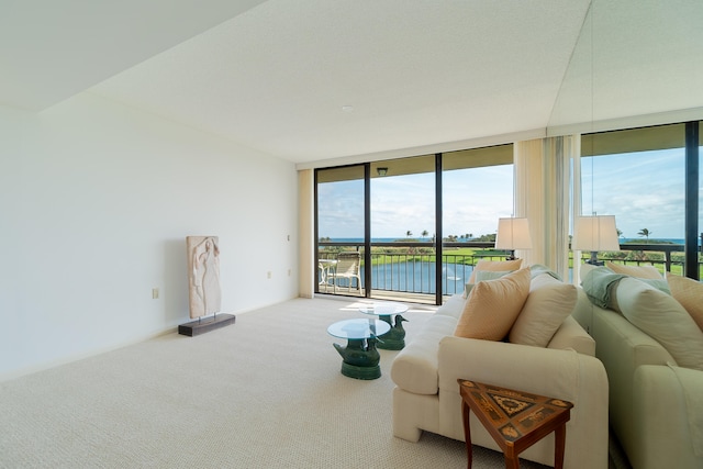 living room with carpet, floor to ceiling windows, and a water view