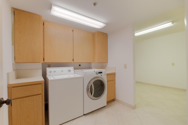 clothes washing area with cabinets, separate washer and dryer, and light tile patterned flooring