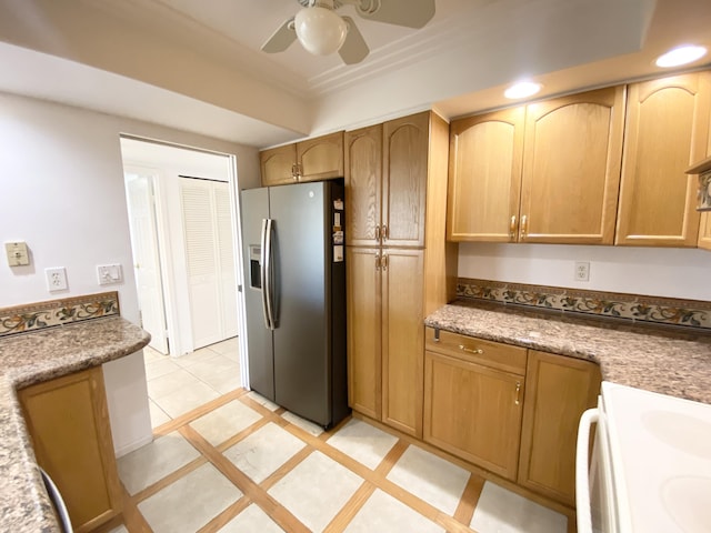 kitchen featuring light stone countertops, stainless steel refrigerator with ice dispenser, ceiling fan, light tile patterned floors, and range