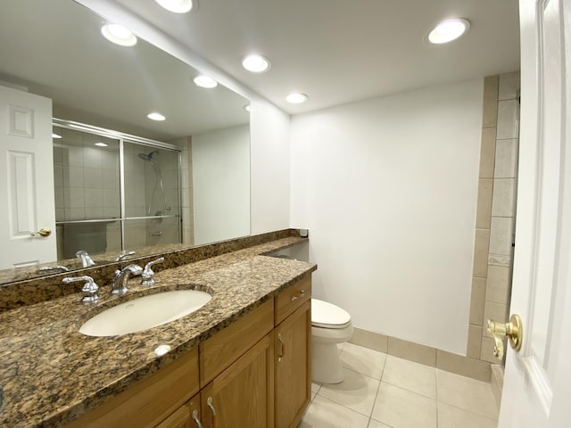 bathroom with tile patterned floors, vanity, a shower with shower door, and toilet