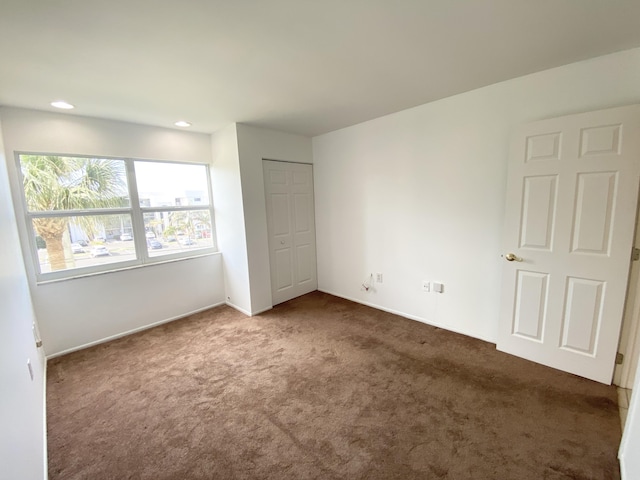 unfurnished bedroom featuring a closet and dark colored carpet