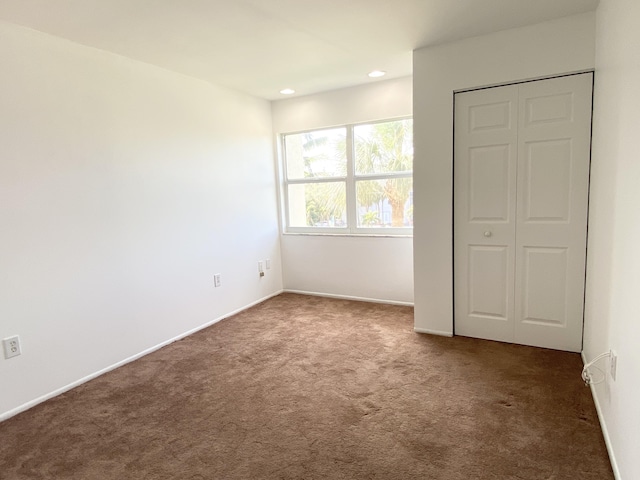 unfurnished bedroom with a closet and dark colored carpet