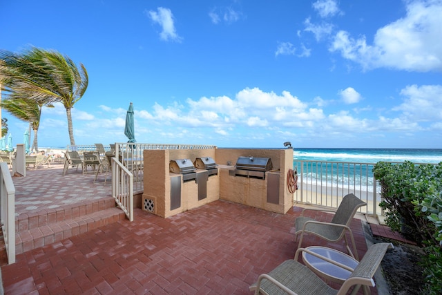 view of patio with a view of the beach, a water view, area for grilling, and exterior kitchen