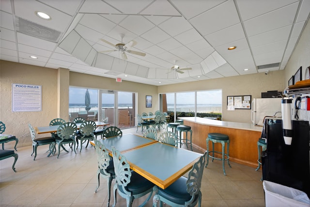 tiled dining area with ceiling fan and a drop ceiling