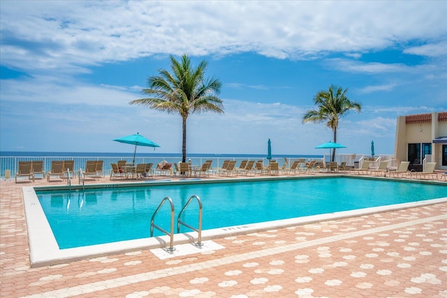 view of swimming pool with a patio area and a water view