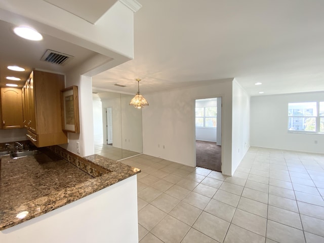 kitchen with a chandelier, a healthy amount of sunlight, light tile patterned floors, and pendant lighting