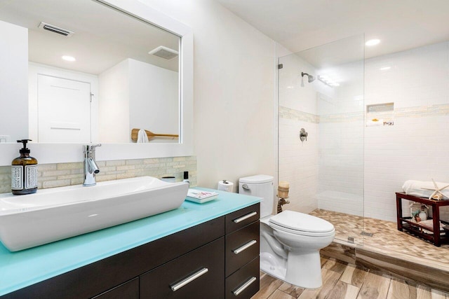 bathroom featuring tiled shower, wood-type flooring, vanity, and toilet