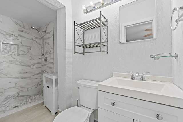 bathroom featuring tiled shower, vanity, and toilet