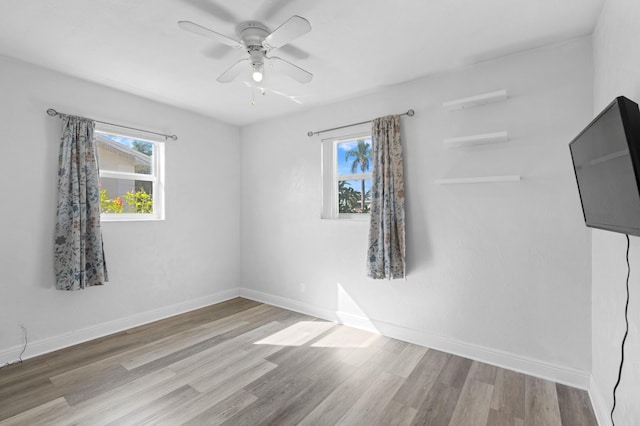 spare room featuring plenty of natural light, ceiling fan, and wood-type flooring