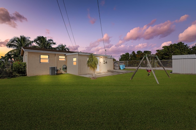 yard at dusk with a playground, central AC, and a patio area