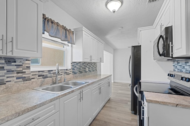 kitchen featuring white cabinets, appliances with stainless steel finishes, light hardwood / wood-style floors, and sink