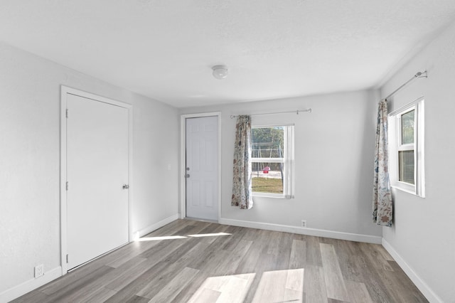 spare room with a textured ceiling and light hardwood / wood-style flooring