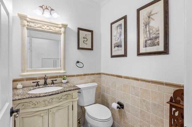 bathroom featuring toilet, tile walls, vanity, and ornamental molding